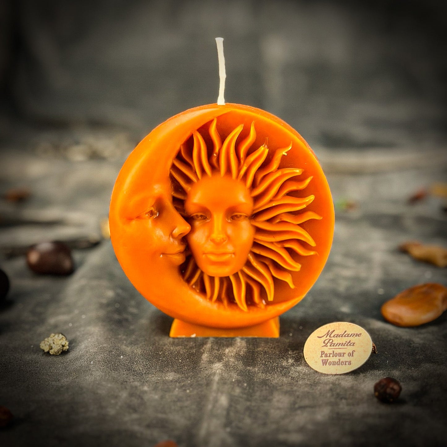 Decorative candle with sun and moon design on a dark surface