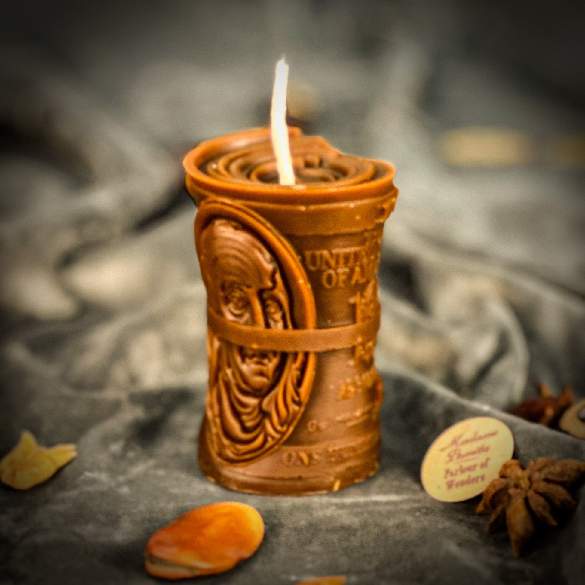 Decorative candle with intricate design on a dark fabric background