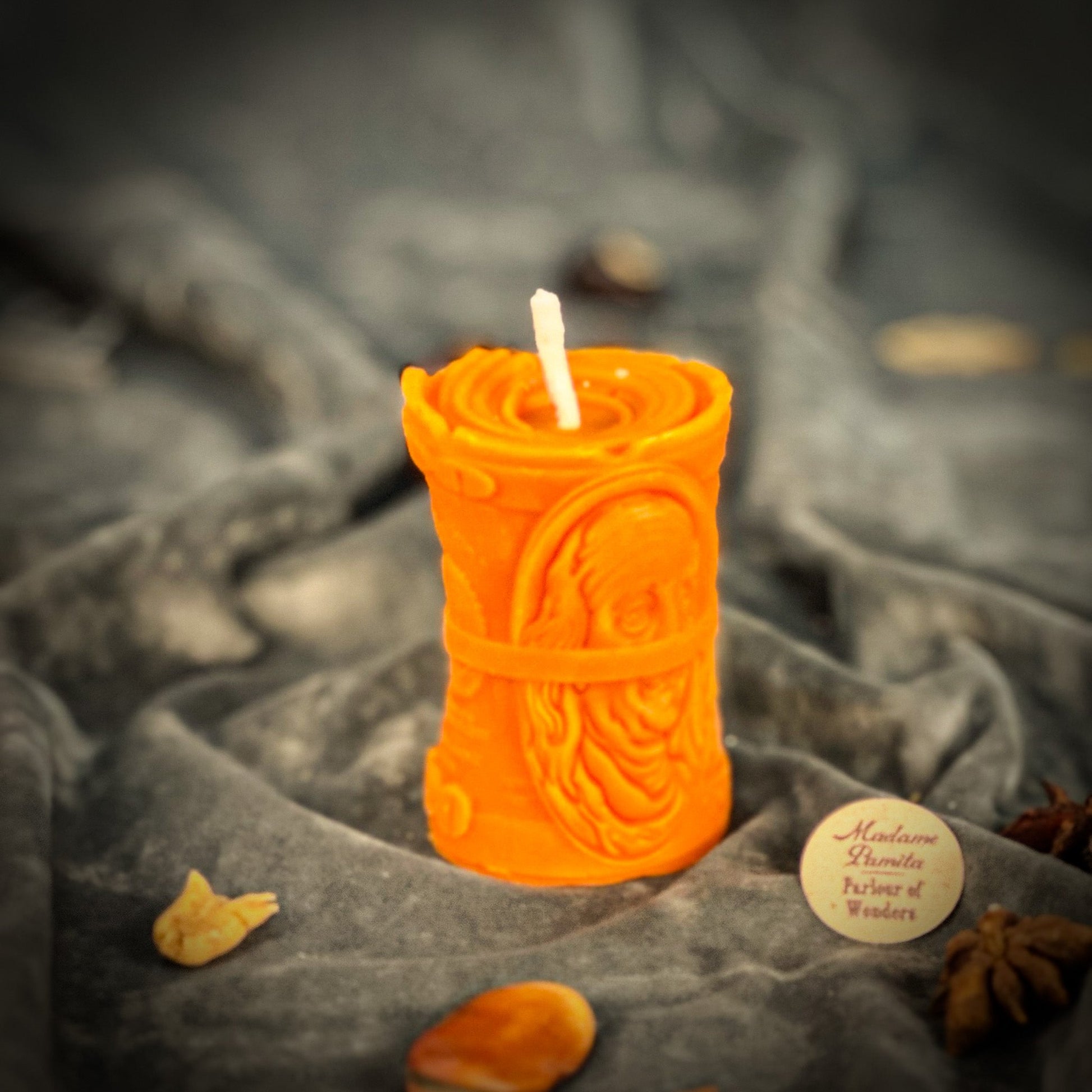 Orange candle with intricate design on a textured gray surface