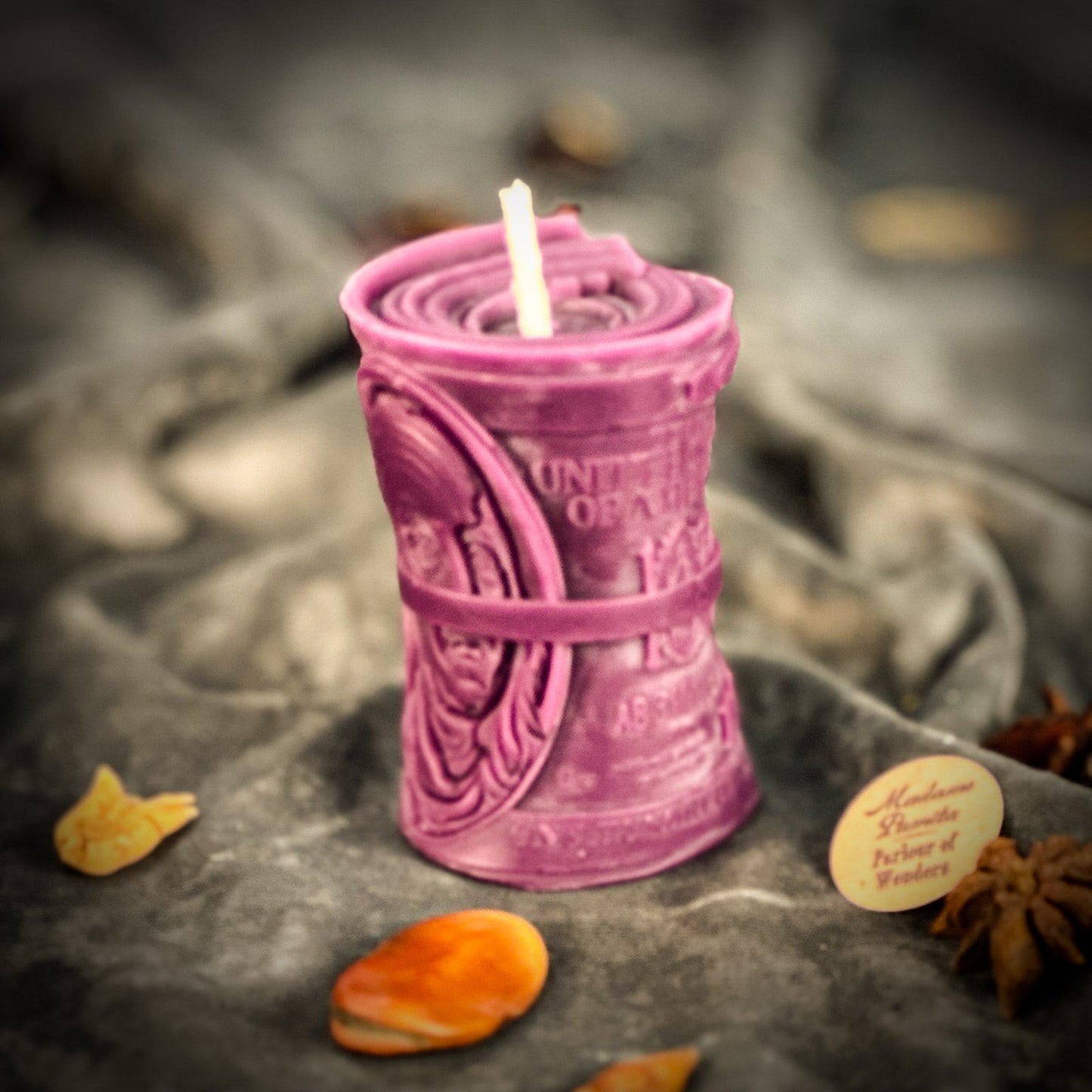 Purple candle with intricate design on a dark surface with decorative elements