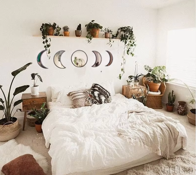 Cozy bedroom with white bedding, plants, and decorative moon phases on the wall.