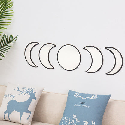 Decorative wall stickers of moon phases on a light gray wall with two pillows featuring deer designs.