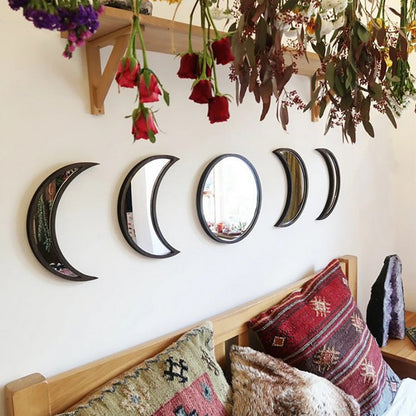 Decorative mirrors shaped like crescent moons on a wall above a bed with patterned pillows.
