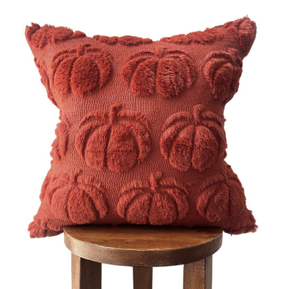Red textured pillow with pumpkin pattern on a wooden stool against a white background