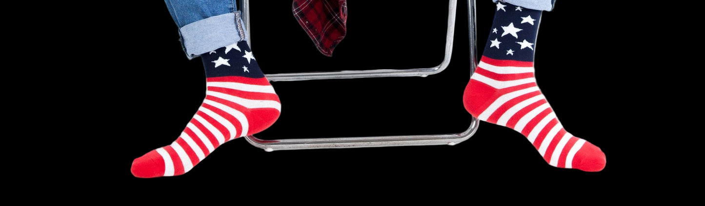 Person wearing American flag socks sitting on a chair with a white background