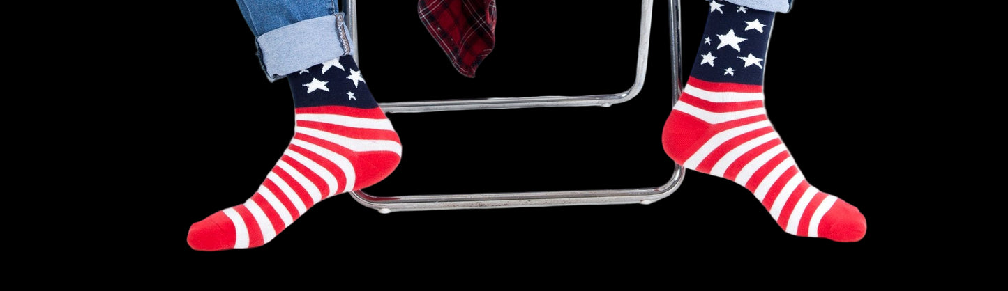 Person wearing American flag socks sitting on a chair with a white background