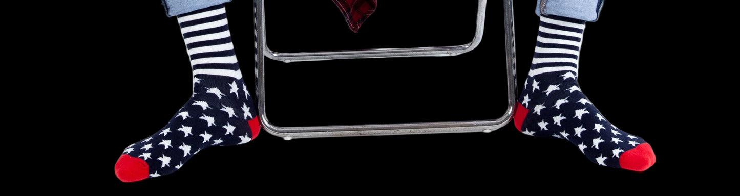 Person wearing ripped jeans and star-patterned socks sitting on a white stool.