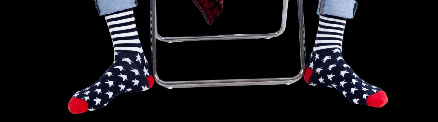 Person wearing ripped jeans and star-patterned socks sitting on a white stool.