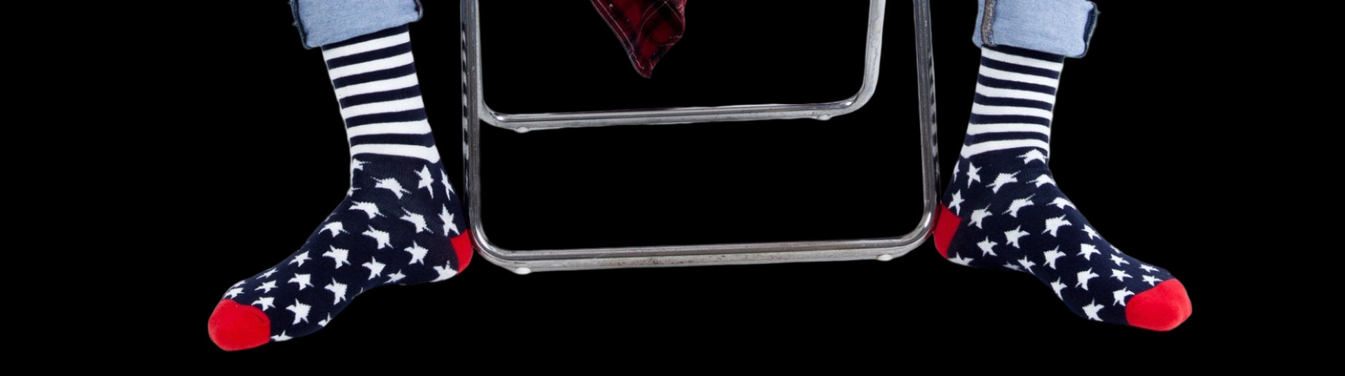 Person wearing ripped jeans and star-patterned socks sitting on a white stool.