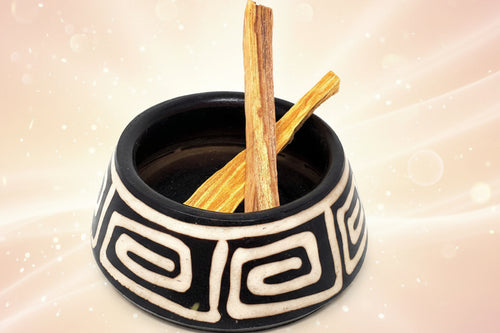 Ceramic bowl with black and white patterns containing two wooden sticks on a white background