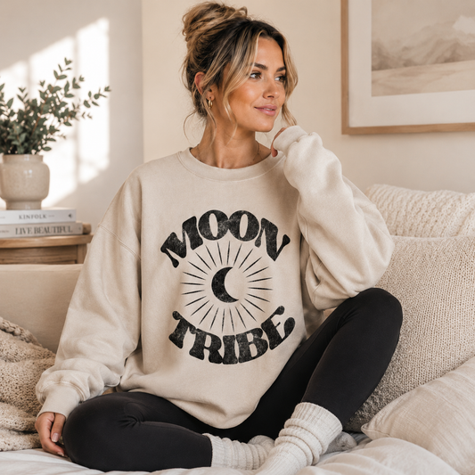 Woman wearing a 'Moon Tribe' sweatshirt sitting on a couch in a cozy living room.