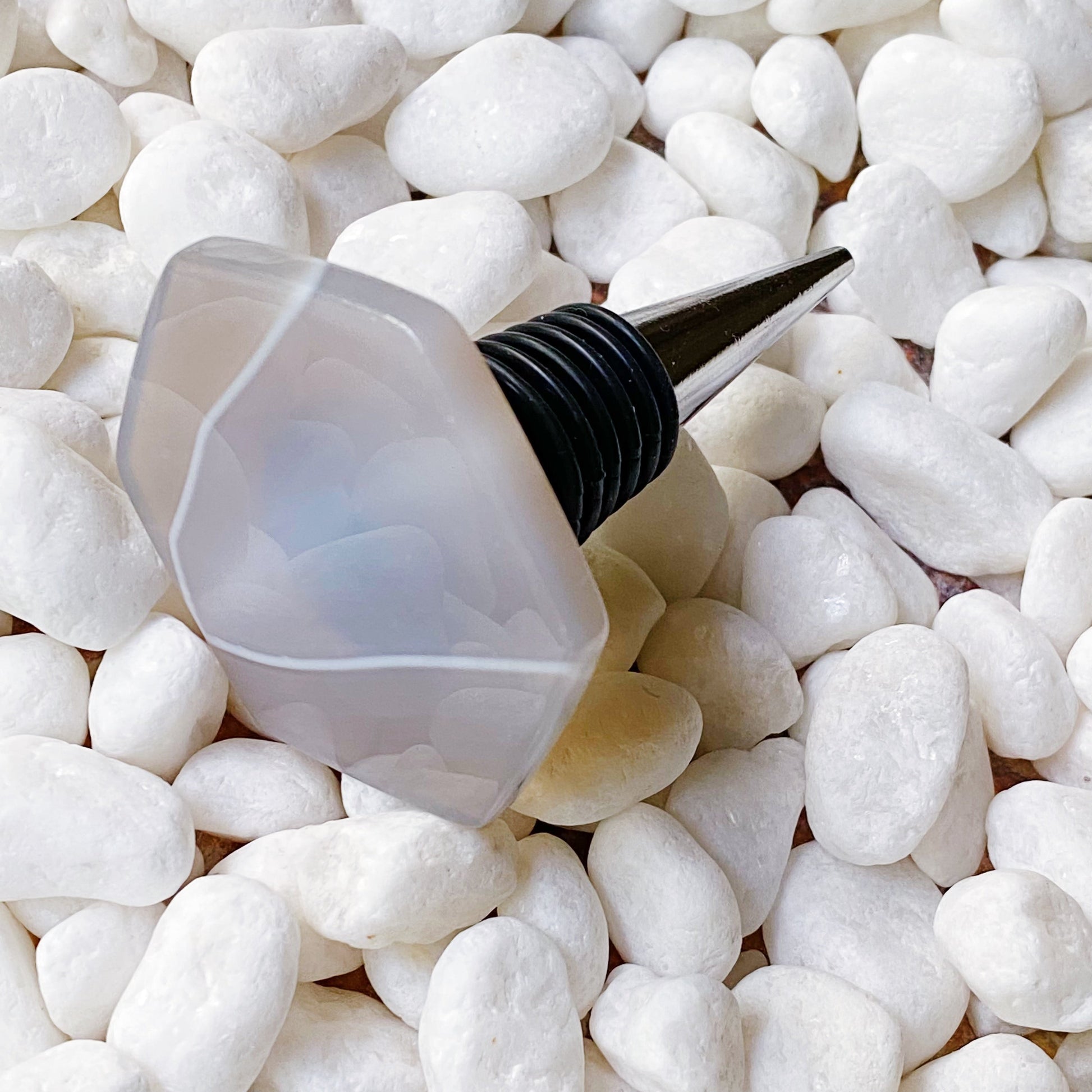 Bottle stopper shaped like a light bulb on white pebbles