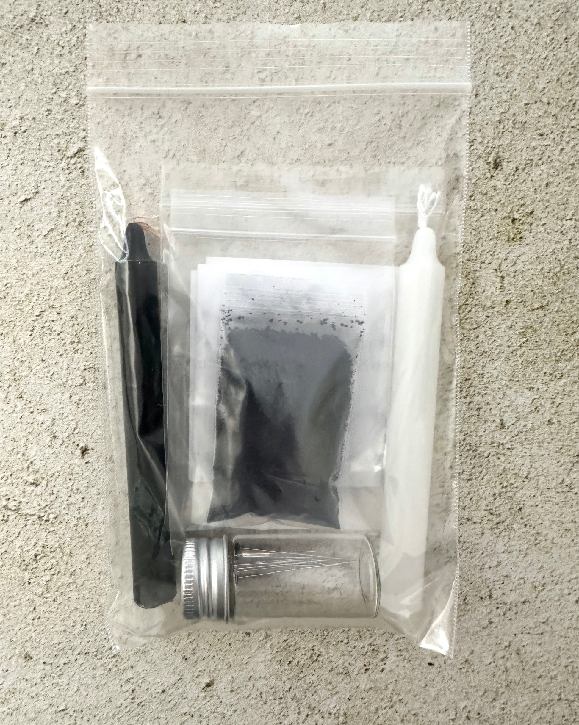Clear plastic bag with grooming items including a brush, scissors, and a small container on a textured surface.