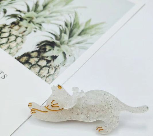 Decorative cat-shaped object on a white surface with a blurred pineapple in the background