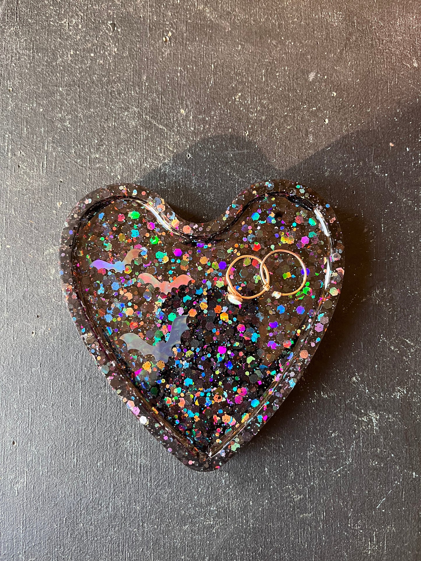 Heart-shaped object with glittery finish on a dark surface