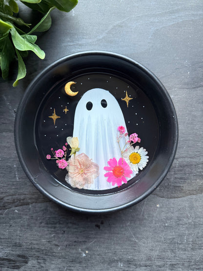 Decorative plate with a ghost and flowers design on a dark surface