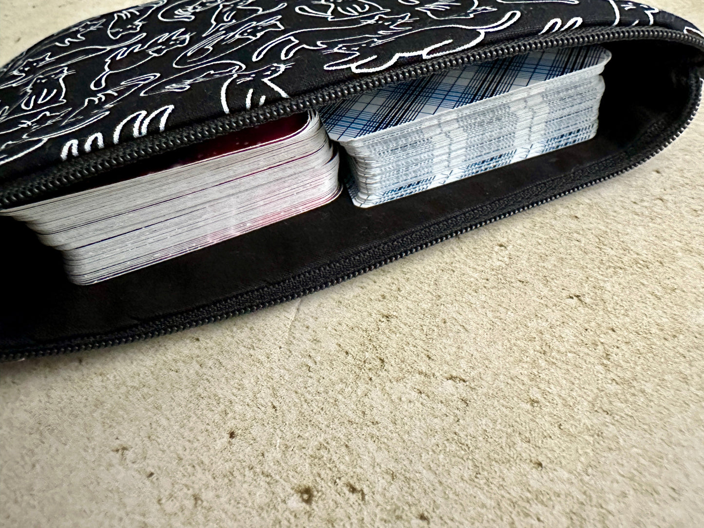 Black case with white patterns containing playing cards on a beige carpet.