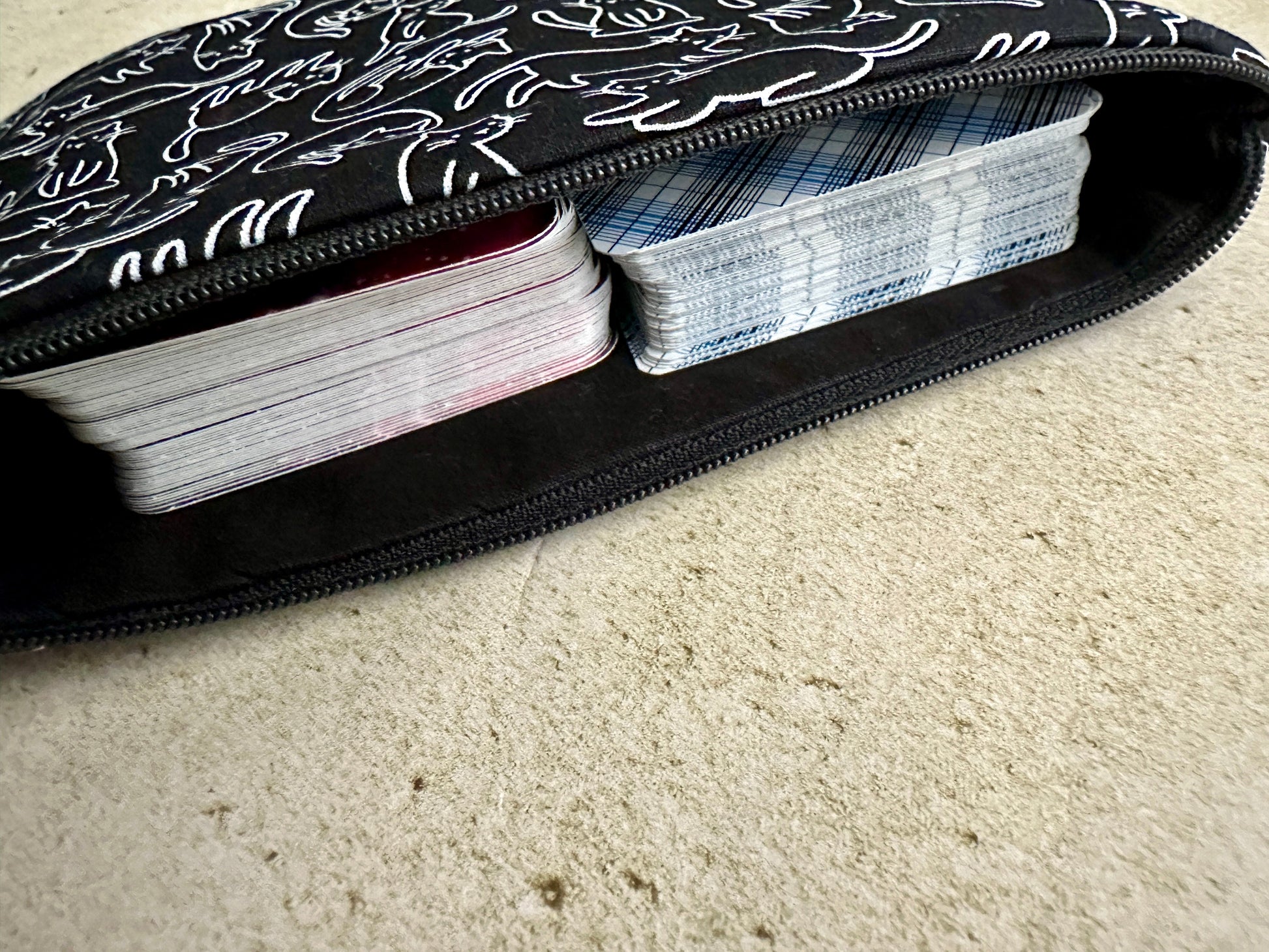 Black case with white patterns containing playing cards on a beige carpet.