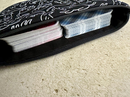 Black case with white patterns containing playing cards on a beige carpet.
