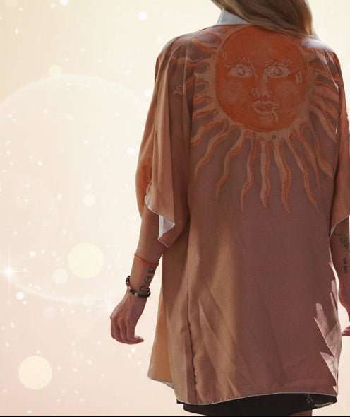 Person wearing a peach-colored kimono with a sun design in a forest setting