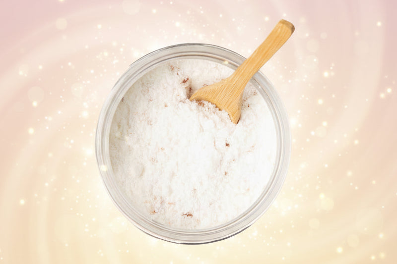 Jar of coconut oil with a wooden spoon on a white background