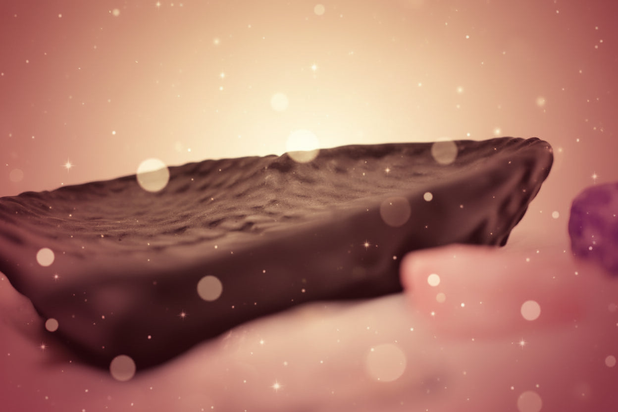 Black rectangular stone on a white surface with blurred stones in the background