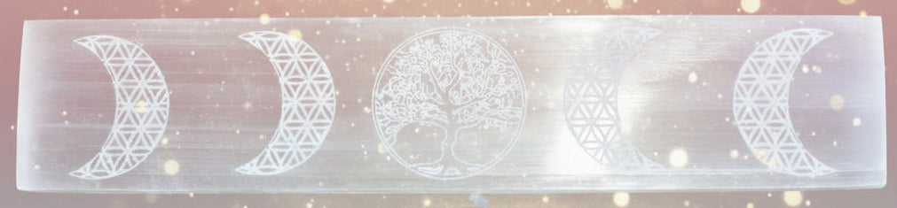 Set of crystals on a wooden surface with a selenite slab featuring moon phase designs.