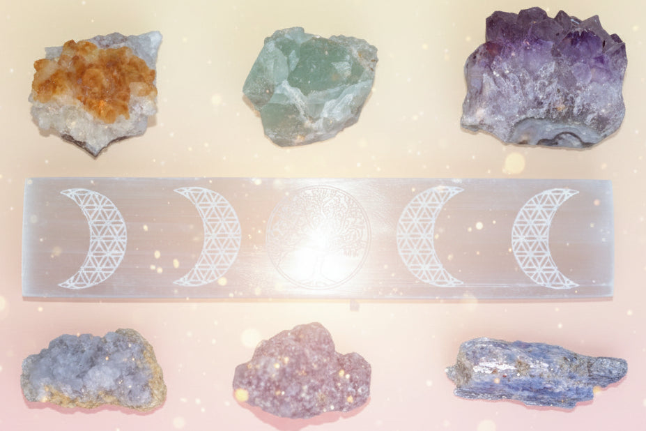 Set of crystals and a selenite slab with moon phase design on a wooden surface
