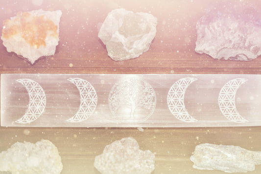 Crystal stones with a selenite slab featuring lunar phases on a wooden surface