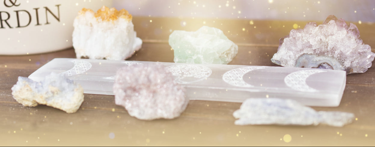 Collection of crystals and a crystal holder on a wooden surface with a blurred background.