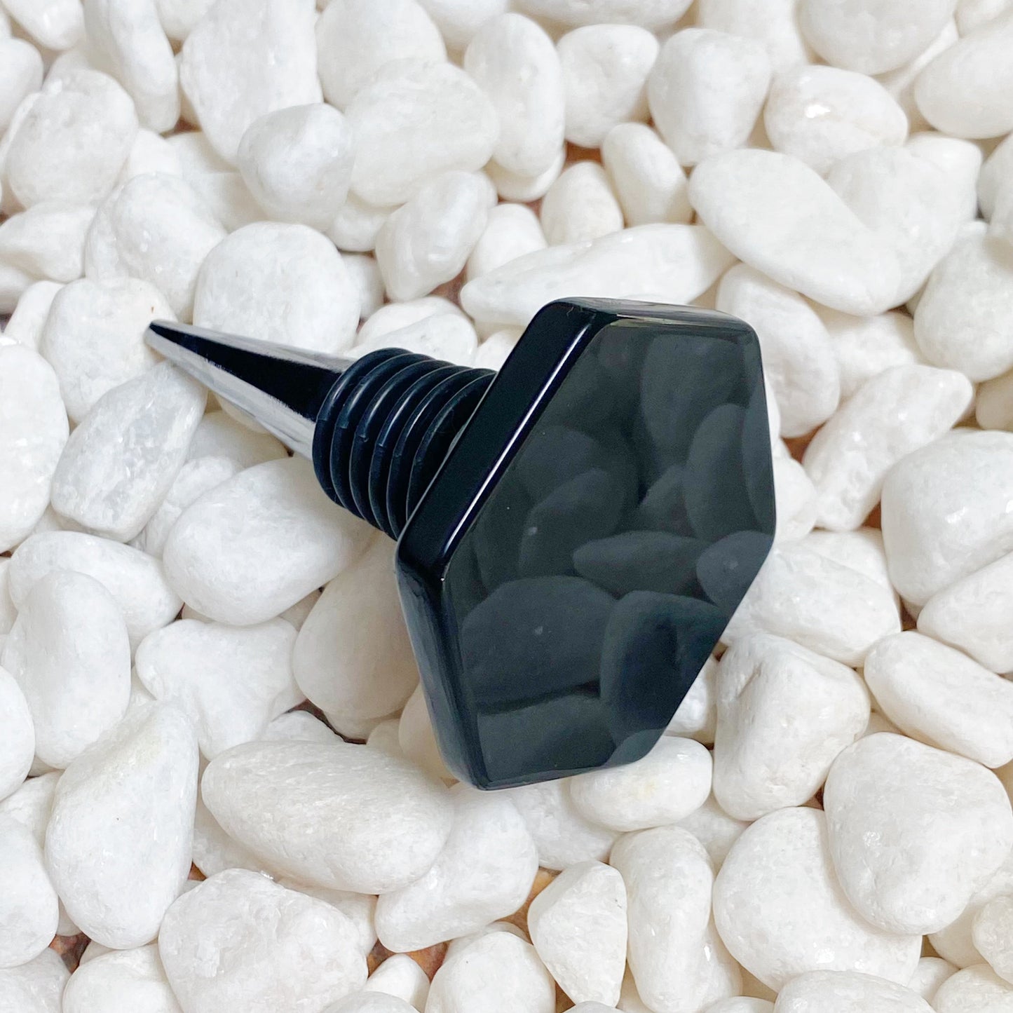 Black bottle stopper on white pebbles