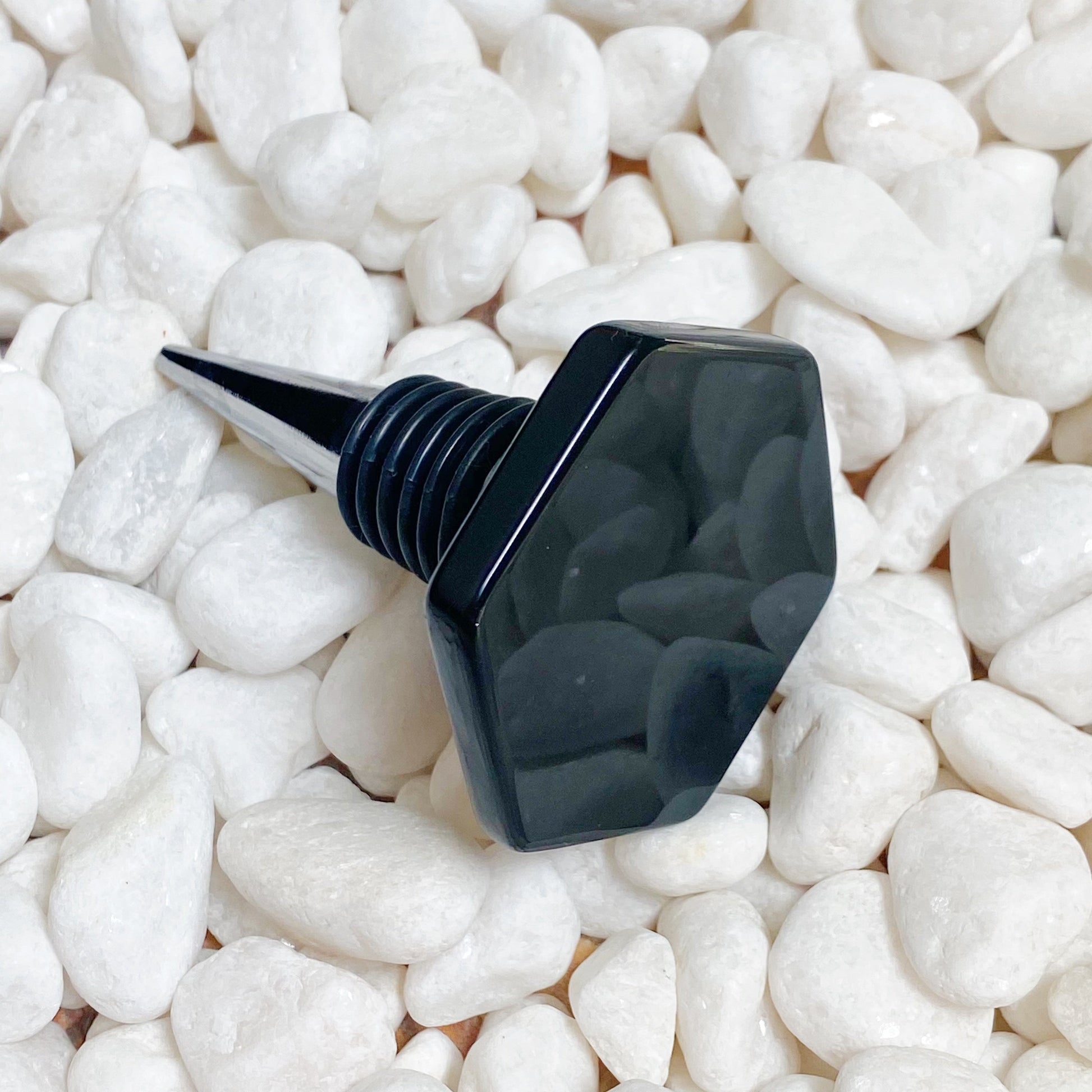 Black bottle stopper on white pebbles