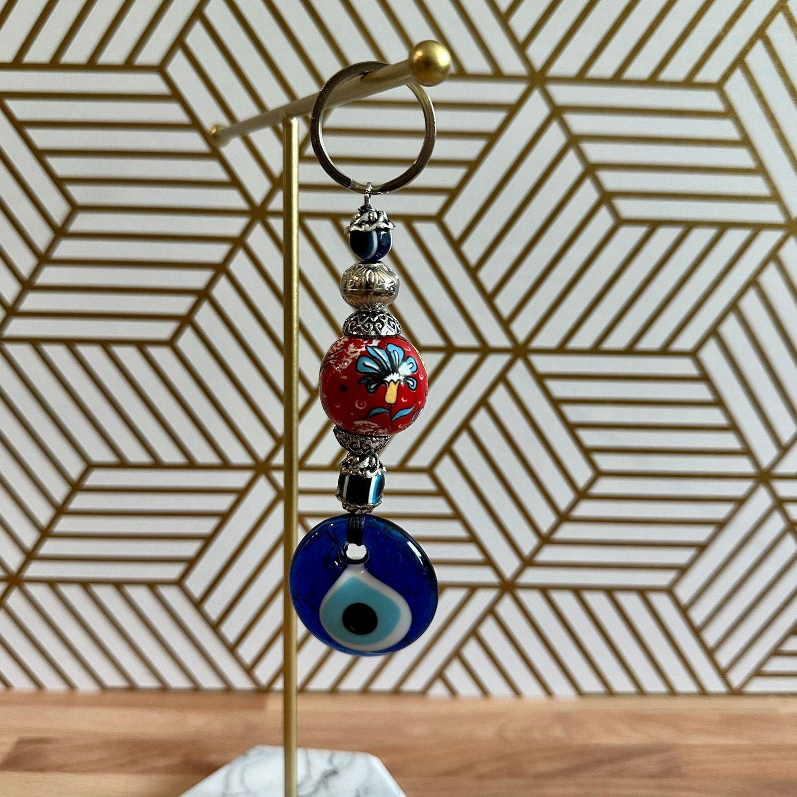 Decorative keychain with beads on a stand against a geometric patterned wall.