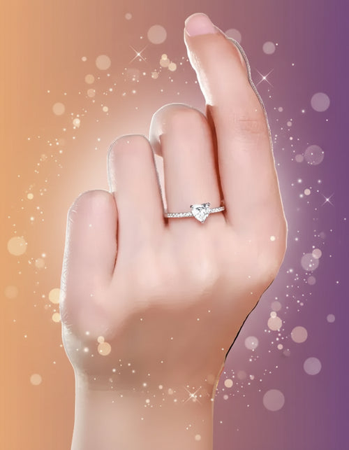 Heart-shaped diamond ring on a finger against a neutral background