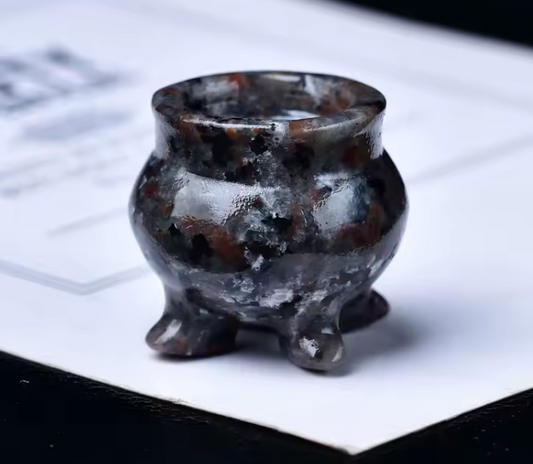 Small brown and black ceramic pot on a white surface