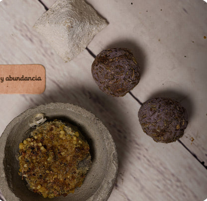 Mortar and pestle with ground herbs on a wooden surface, accompanied by a small stone and a label.