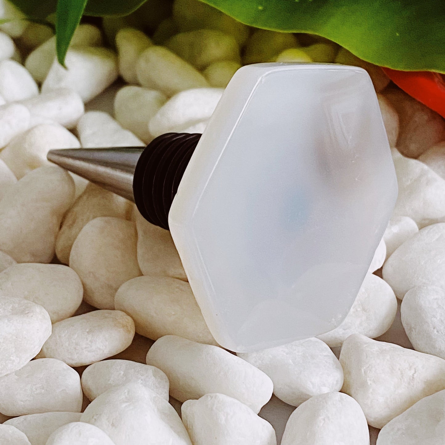 White bottle stopper with black cap on pebbles