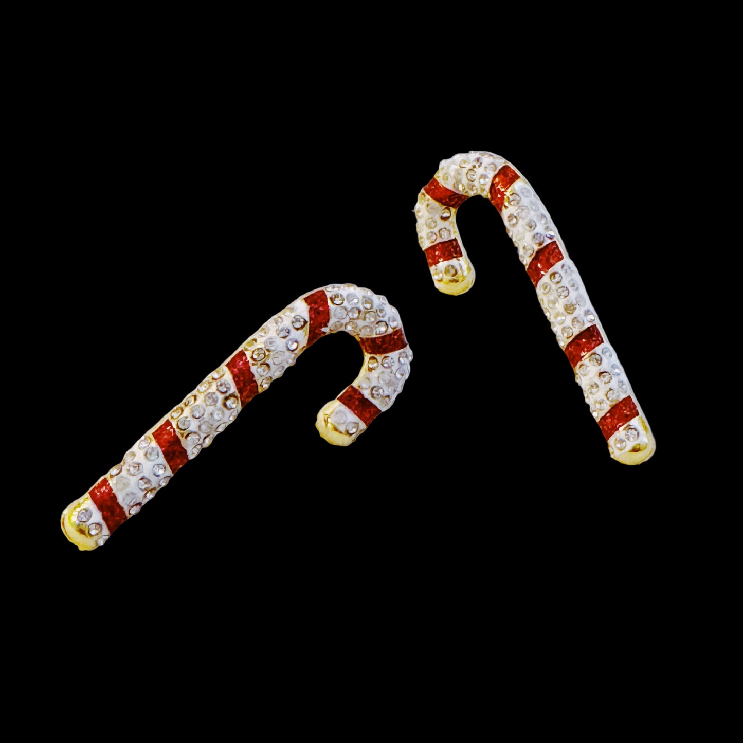 Candy cane-shaped earrings with red and white stripes on a light gray background