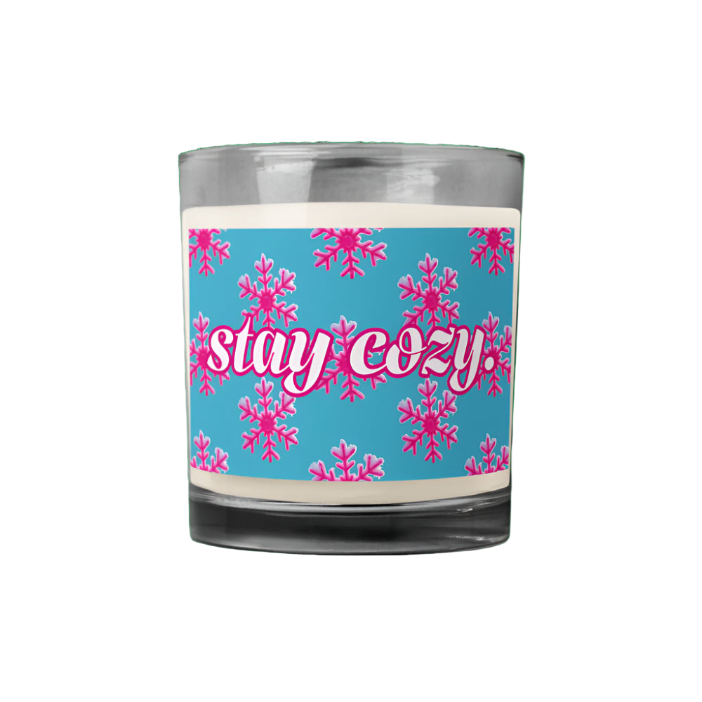 Candle with a blue label featuring pink snowflakes and 'stay cozy' text on a white background.