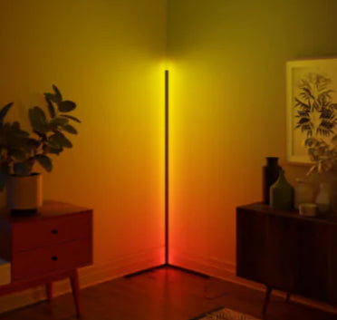 Corner floor lamp casting a warm glow in a room with furniture and plants.