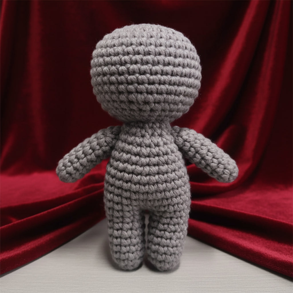 Gray crochet doll on a light surface with a neutral background