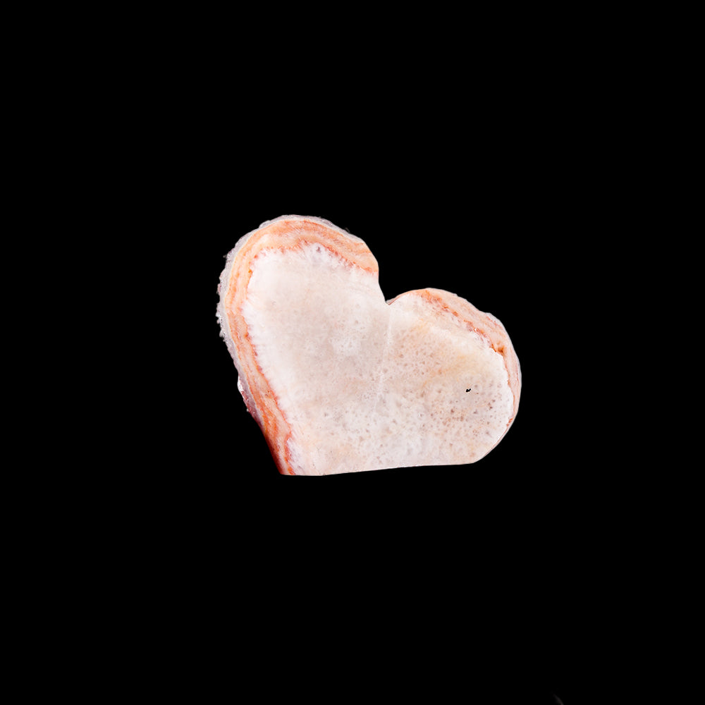 Heart-shaped stone held between fingers on a white background