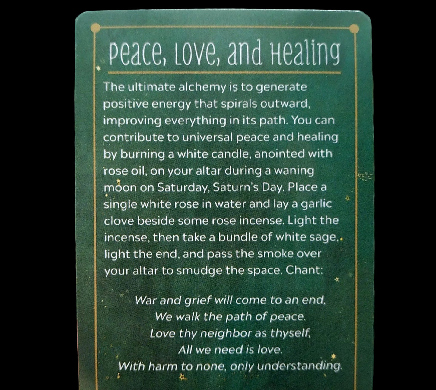 Green card with text on peace, love, and healing rituals held by a hand.