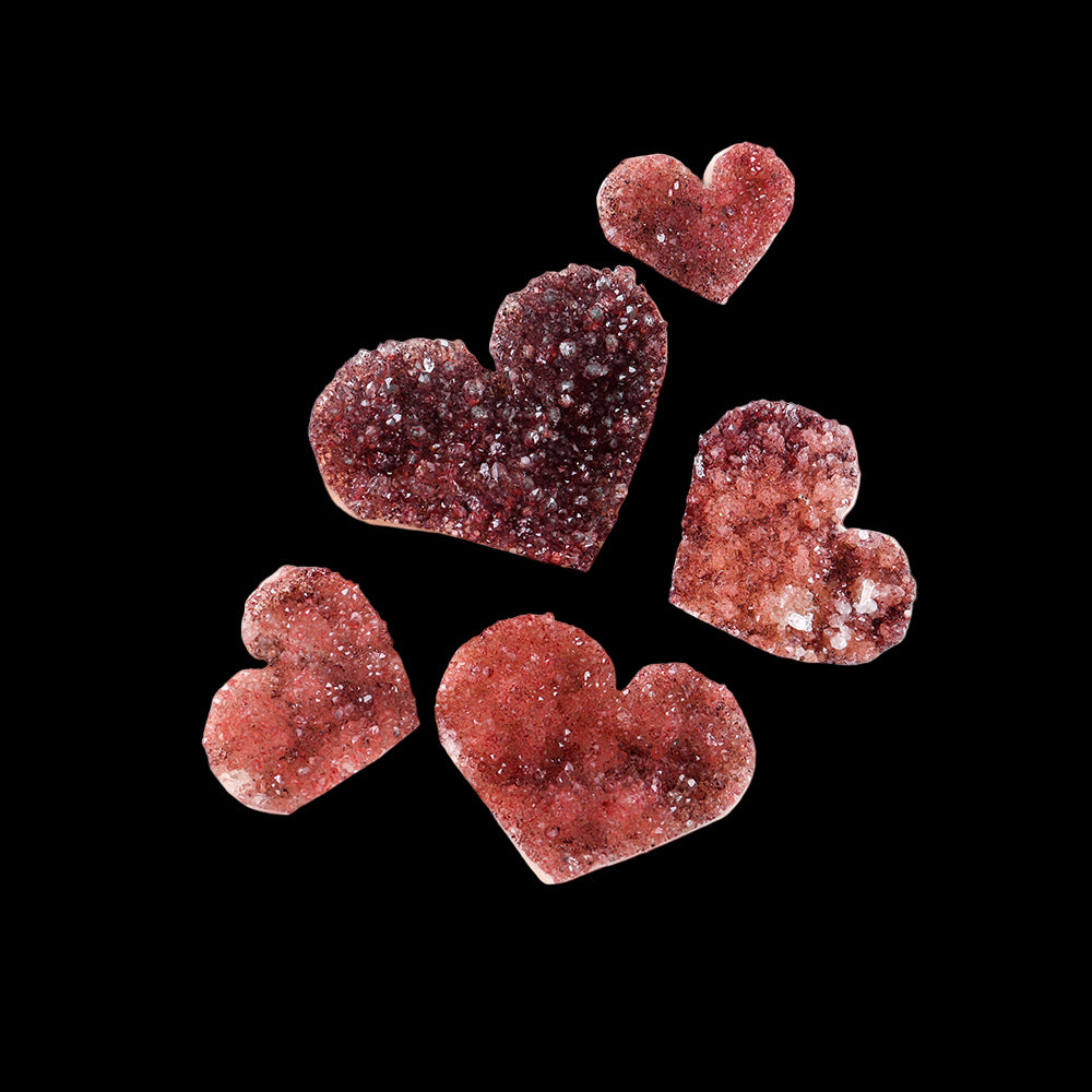 Heart-shaped crystal objects on a hand against a white background