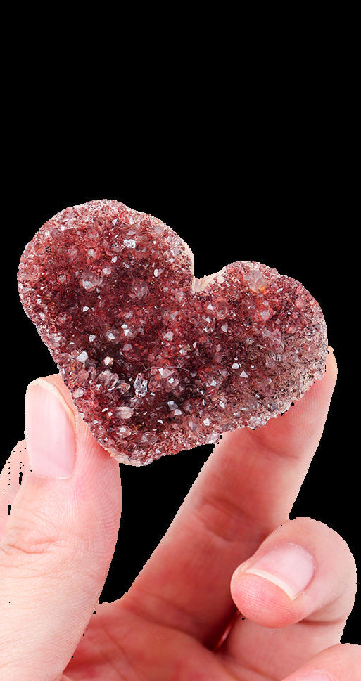 Heart-shaped crystal held between fingers on a white background