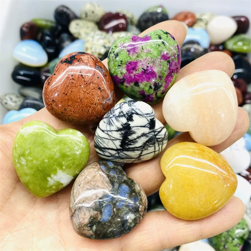 Hand holding various multicolored polished stones with a blurred background of more stones.