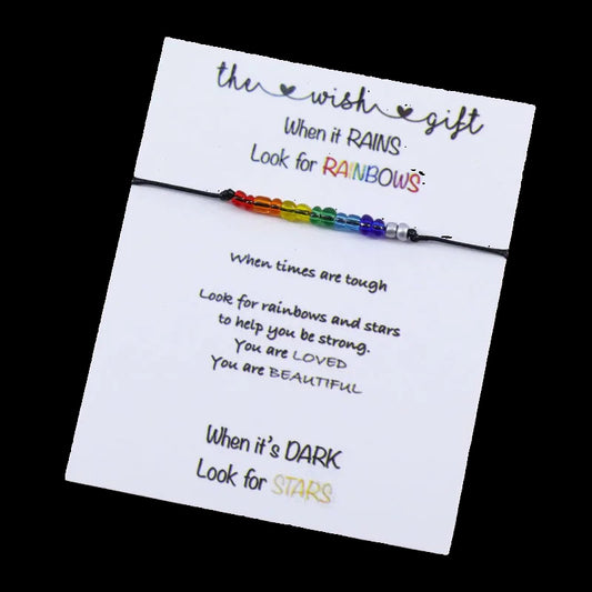 Rainbow beaded bracelet on a card with motivational text on a wooden surface
