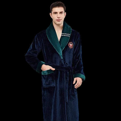 Man wearing a dark blue robe with green trim against a white wall.
