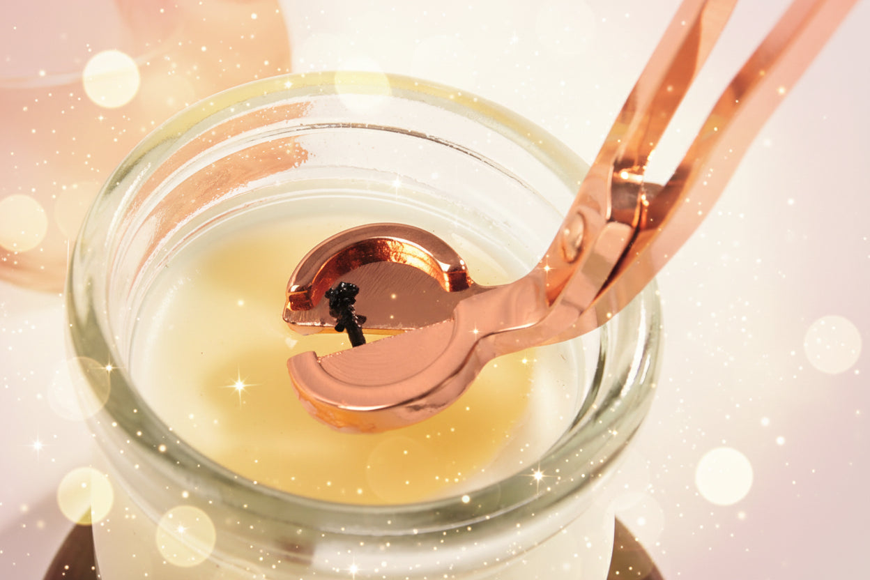 Rose gold spoon lifting a small amount of yellow liquid from a glass jar.