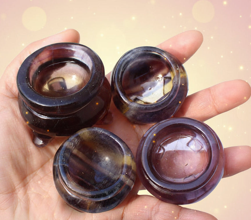 Four dark brown gemstones held in a hand against a white background